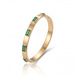 Gold bracelet with emerald green gemstones on a white background