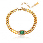 Gold chain bracelet with a green gemstone on a white background