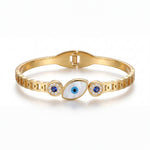 Gold bracelet with eye design and blue stones on a white background