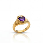 Gold ring with a heart-shaped purple gemstone on a white background