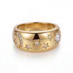 Gold ring with star and moon designs on a white background
