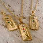 Three gold pendants with intricate designs on a textured beige surface