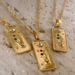 Three gold pendants with intricate designs on a textured beige surface