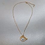 Full view of gold evil eye necklace with twisted chain and lobster clasp, laid flat on silver background, celestial style by Avyrona