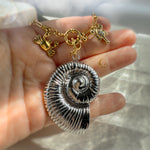 Nerida silver shell necklace held in hand, showcasing texture and golden sea creatures