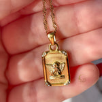 Hand holding the Seraphina angel pendant showing its gold details and textured finish