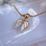 Gold and silver angel wing necklace on a white dish