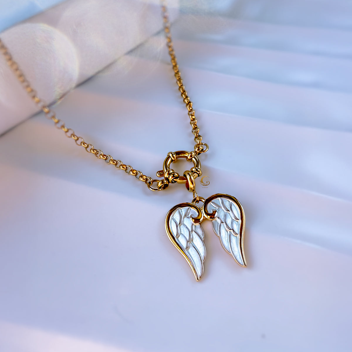 Gold necklace with angel wing pendant on a light background