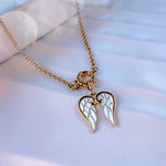 Gold necklace with angel wing pendant on a light background