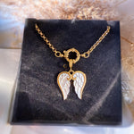 Gold necklace with angel wing pendant on a black display stand.