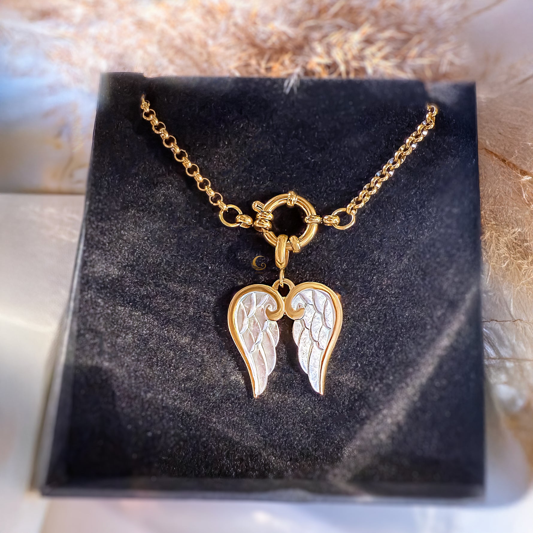 Gold necklace with angel wing pendant on a black display stand.