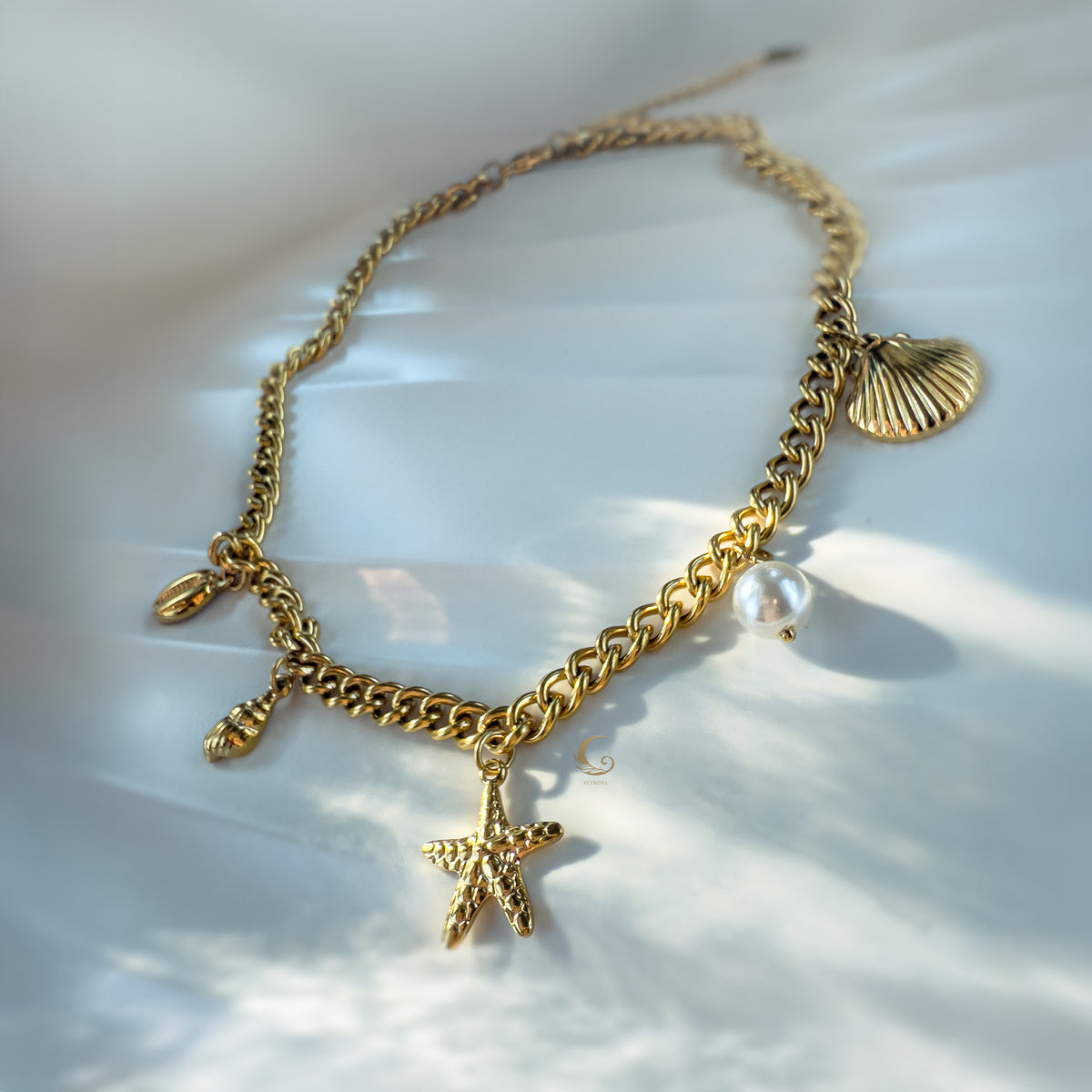 Angled detail of Halina necklace focusing on vegan pearl and golden shell charms on thick chain