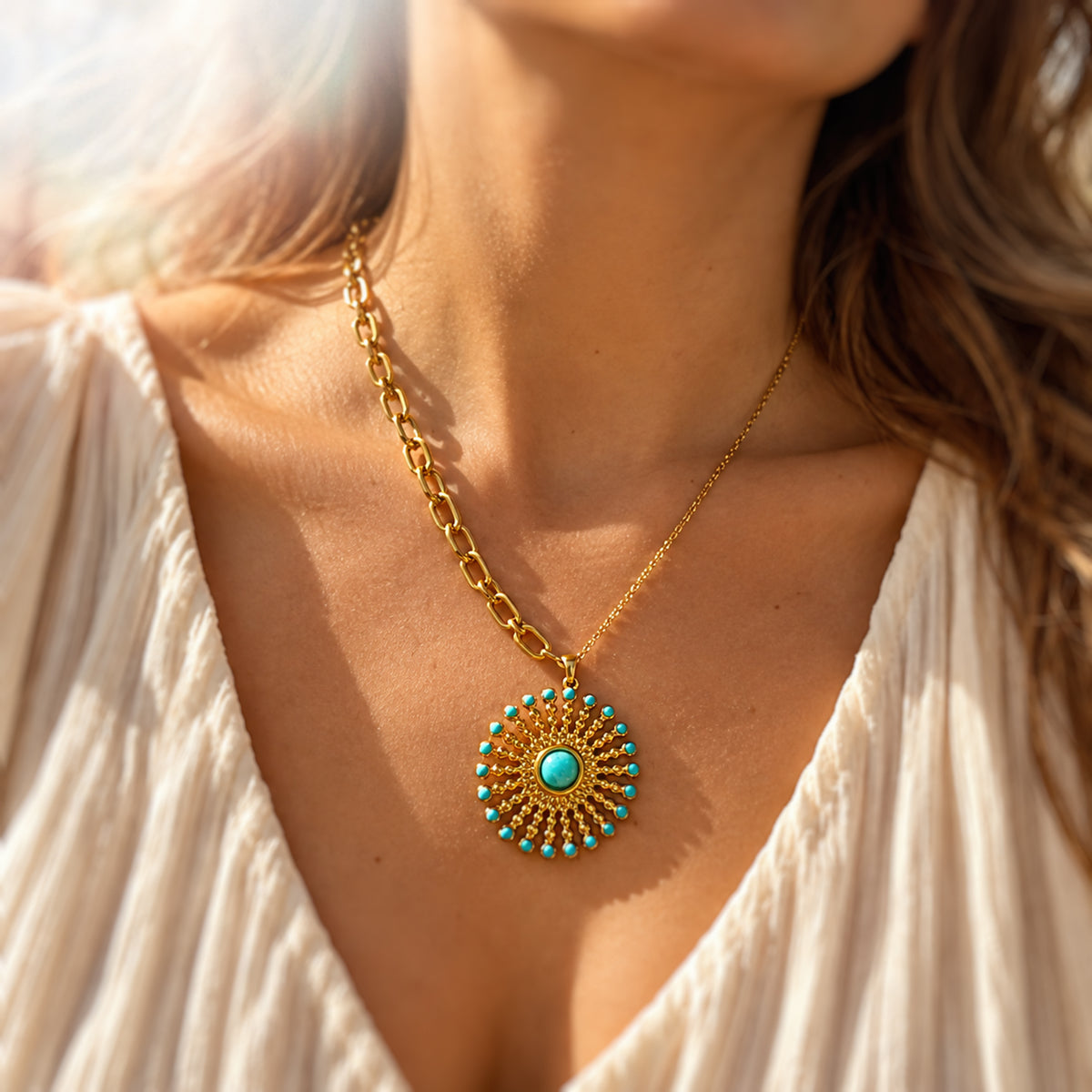 A close-up lifestyle shot of a woman wearing a gold chain necklace with a circular bohemian-style pendant featuring turquoise accents and a central turquoise stone.