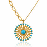 A gold pendant necklace featuring a circular sunburst design with a central turquoise stone and surrounding small turquoise stones, suspended from a gold chain on a white background.