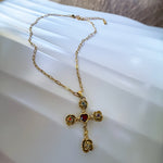Gold necklace with a cross pendant on a white surface
