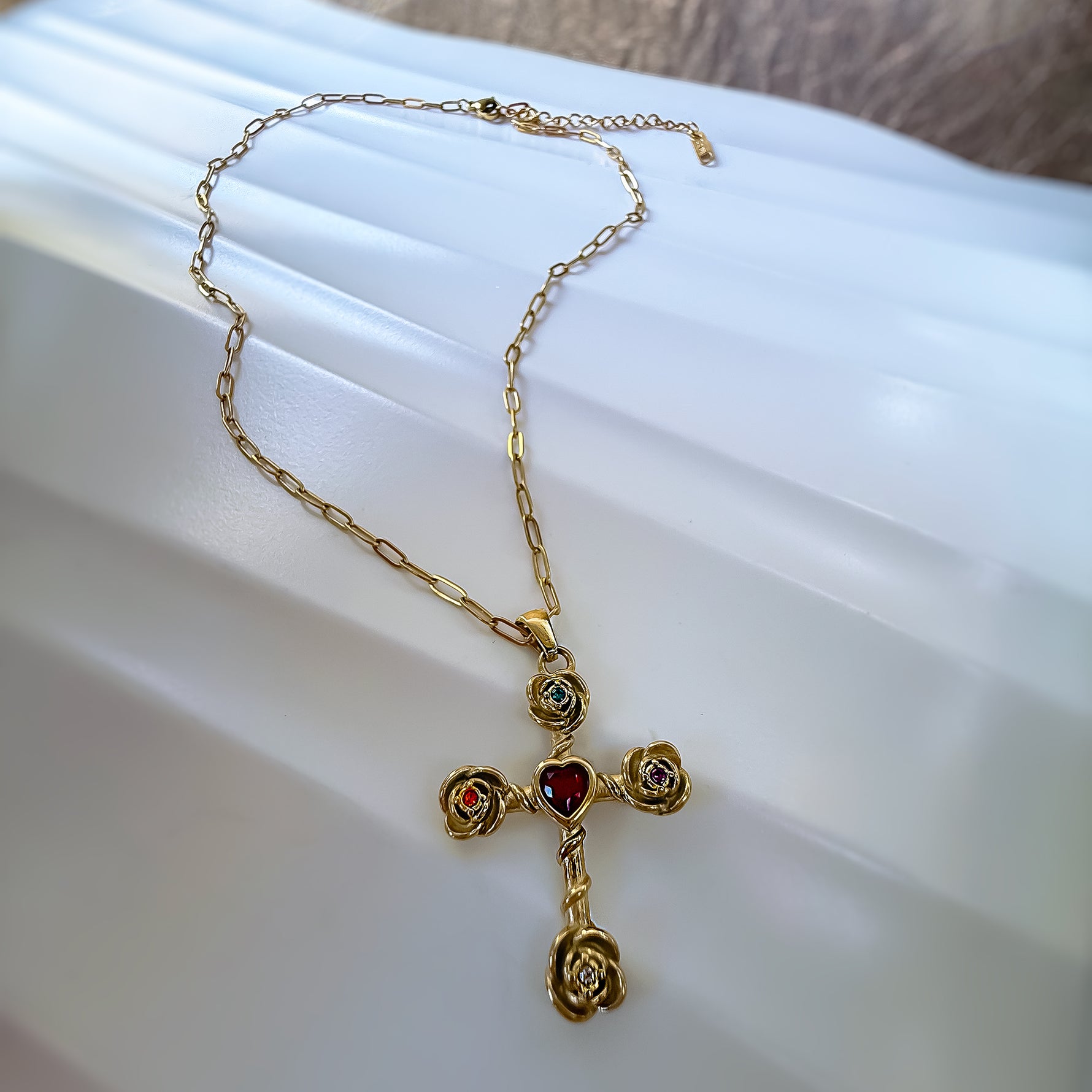 Gold necklace with a cross pendant on a white surface