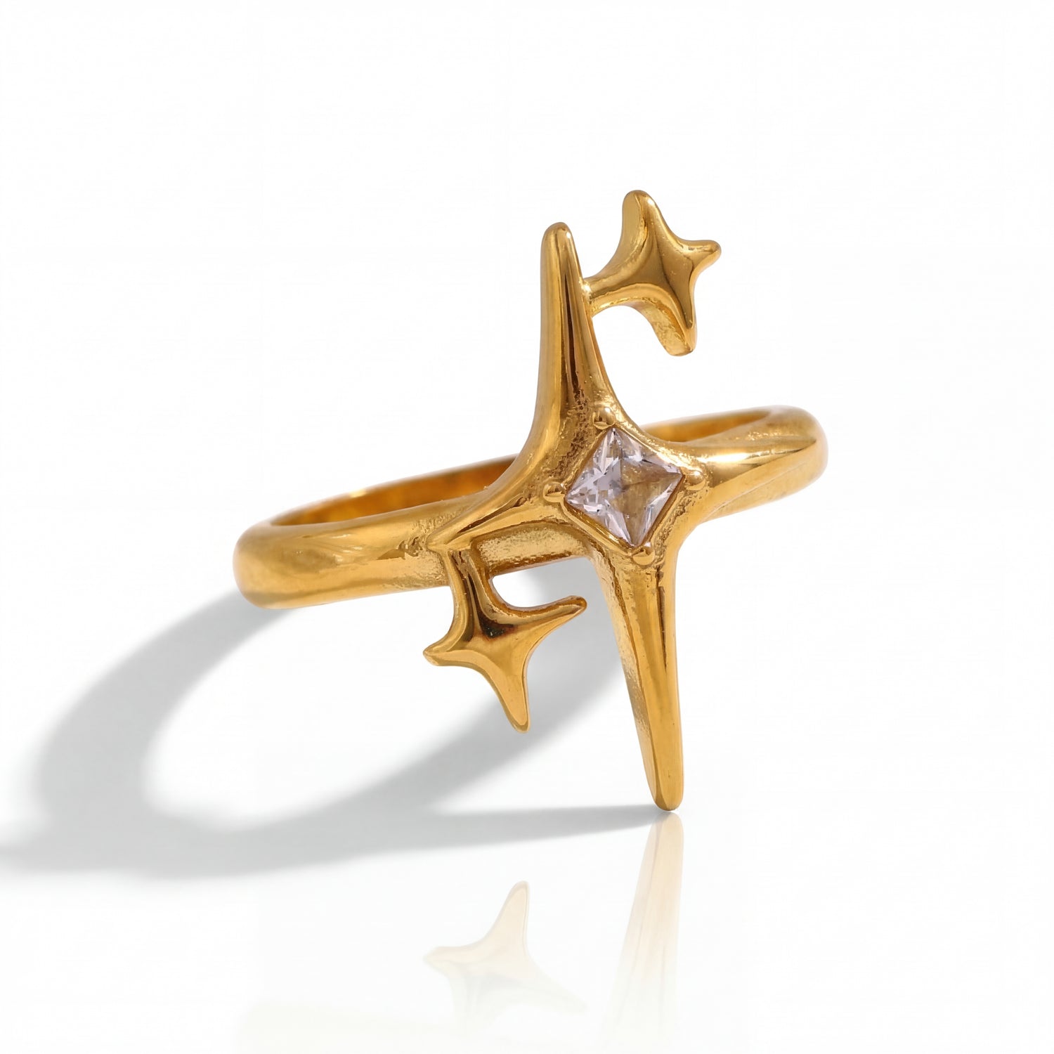 Gold ring with star design and clear gemstone on a white background