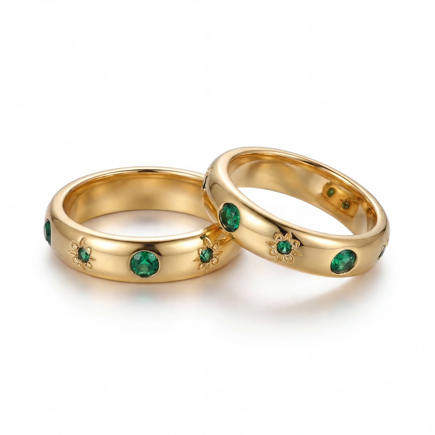 Two gold rings with emerald stones on a white background