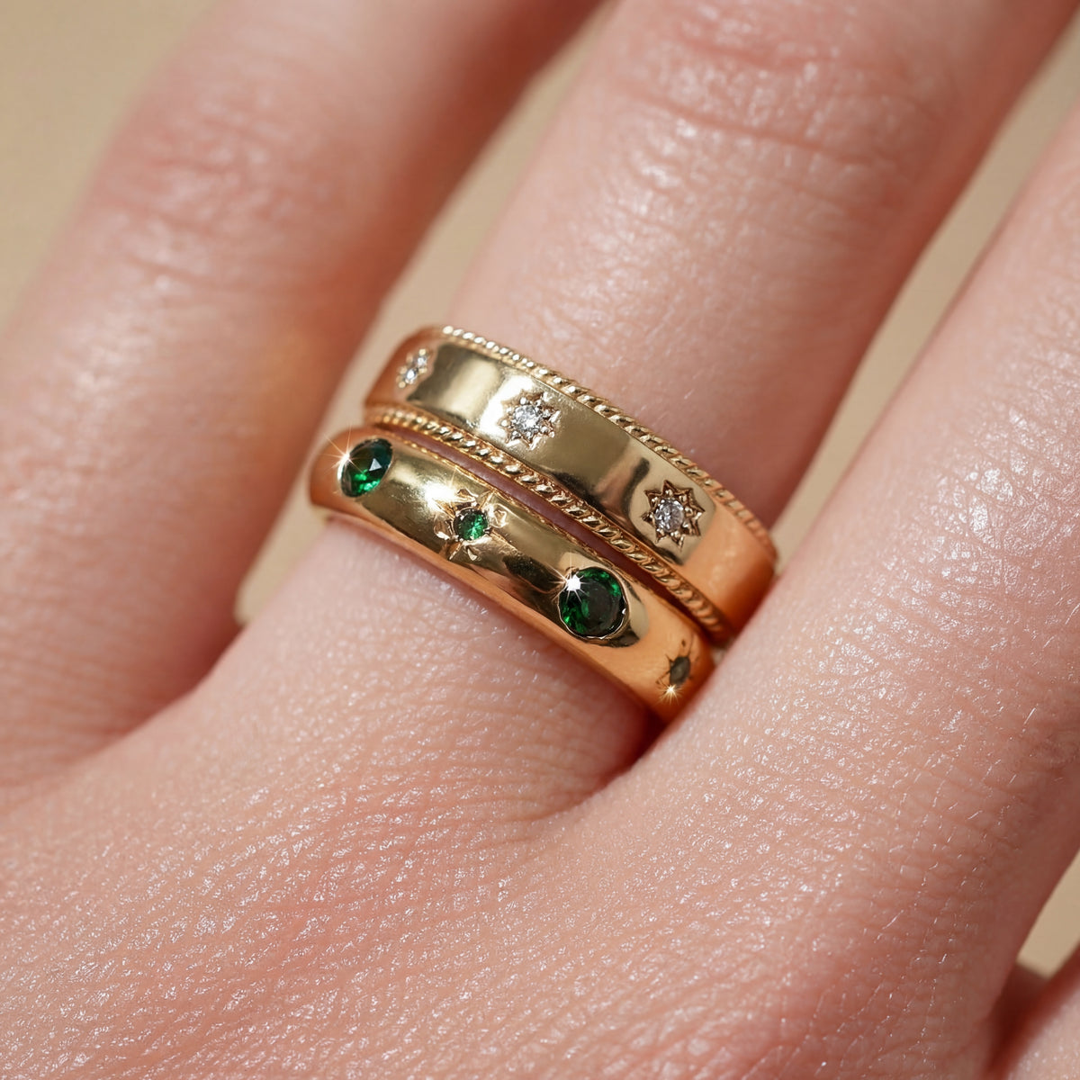 Gold ring with emeralds and diamonds on a finger