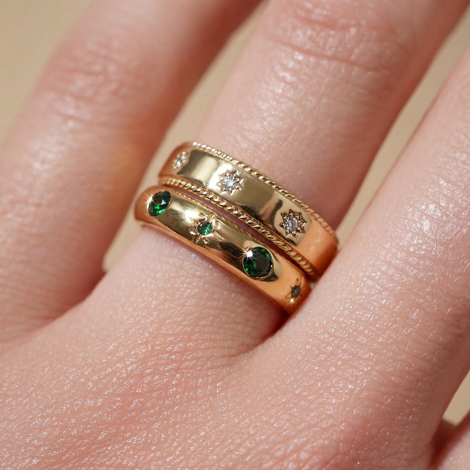 Gold ring with emeralds and diamonds on a finger