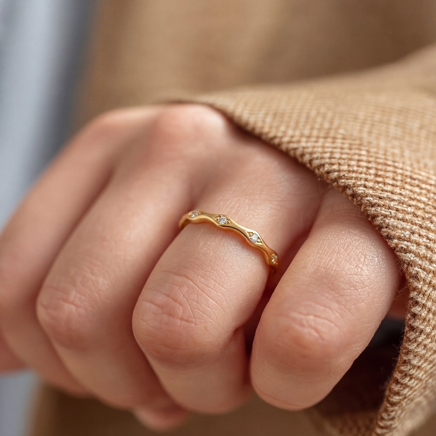 Gold ring on a person's finger with a blurred background
