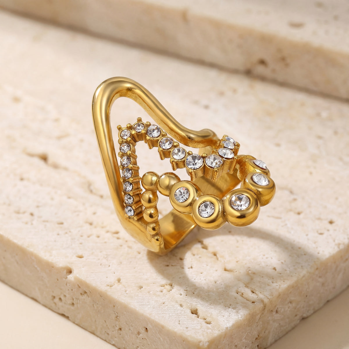 Gold ring with gemstones on a beige stone surface