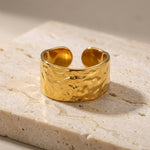 Gold ring with textured surface on a light stone background