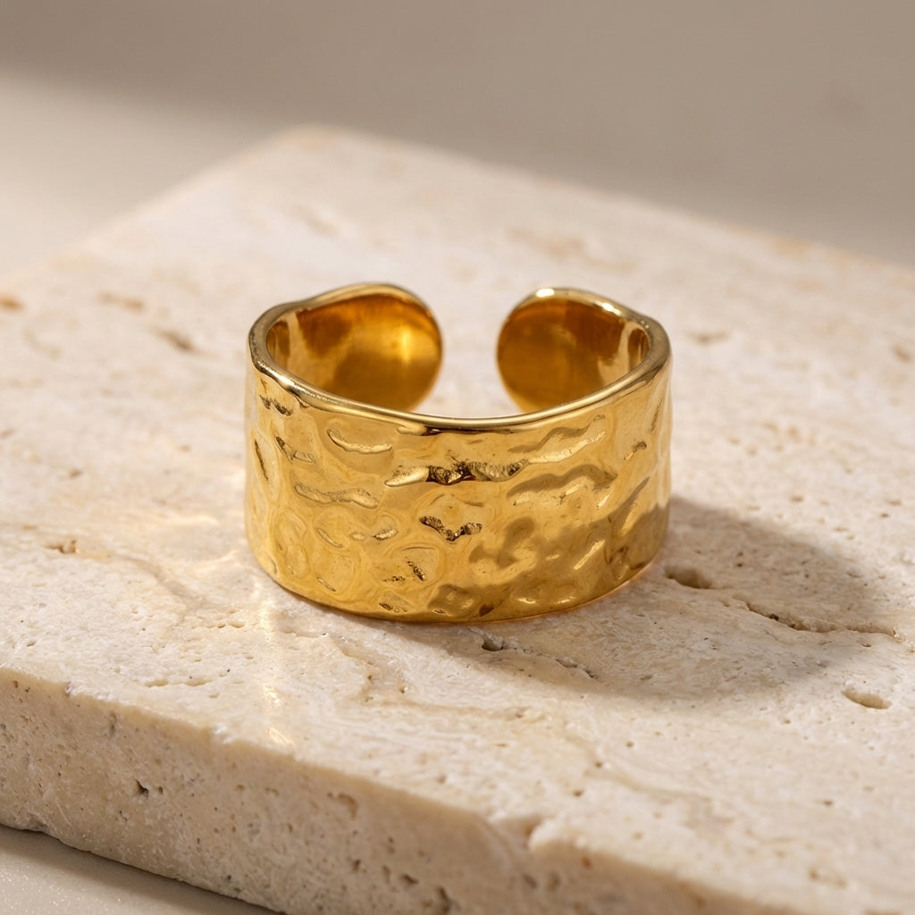 Gold ring with textured surface on a light stone background