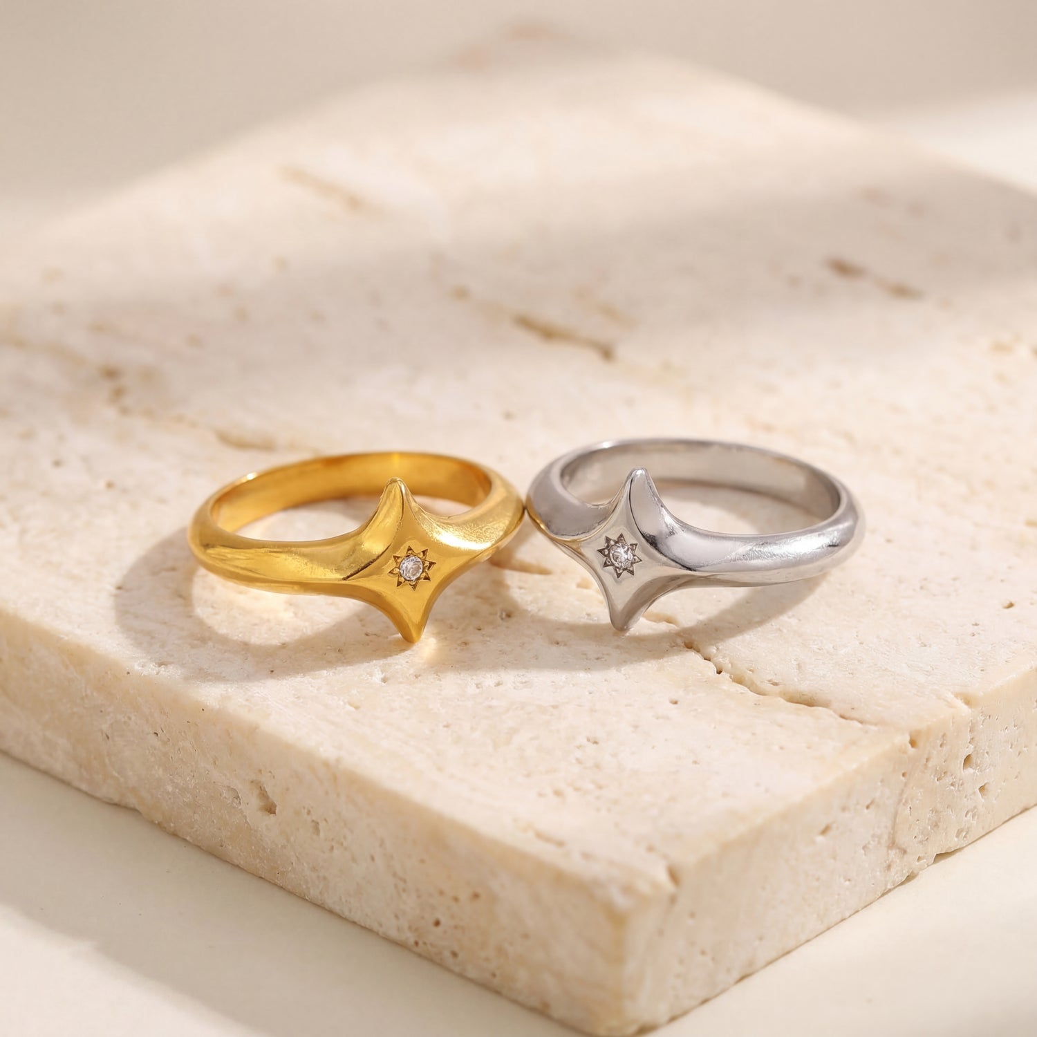 Gold and silver rings with diamond accents on a light stone surface