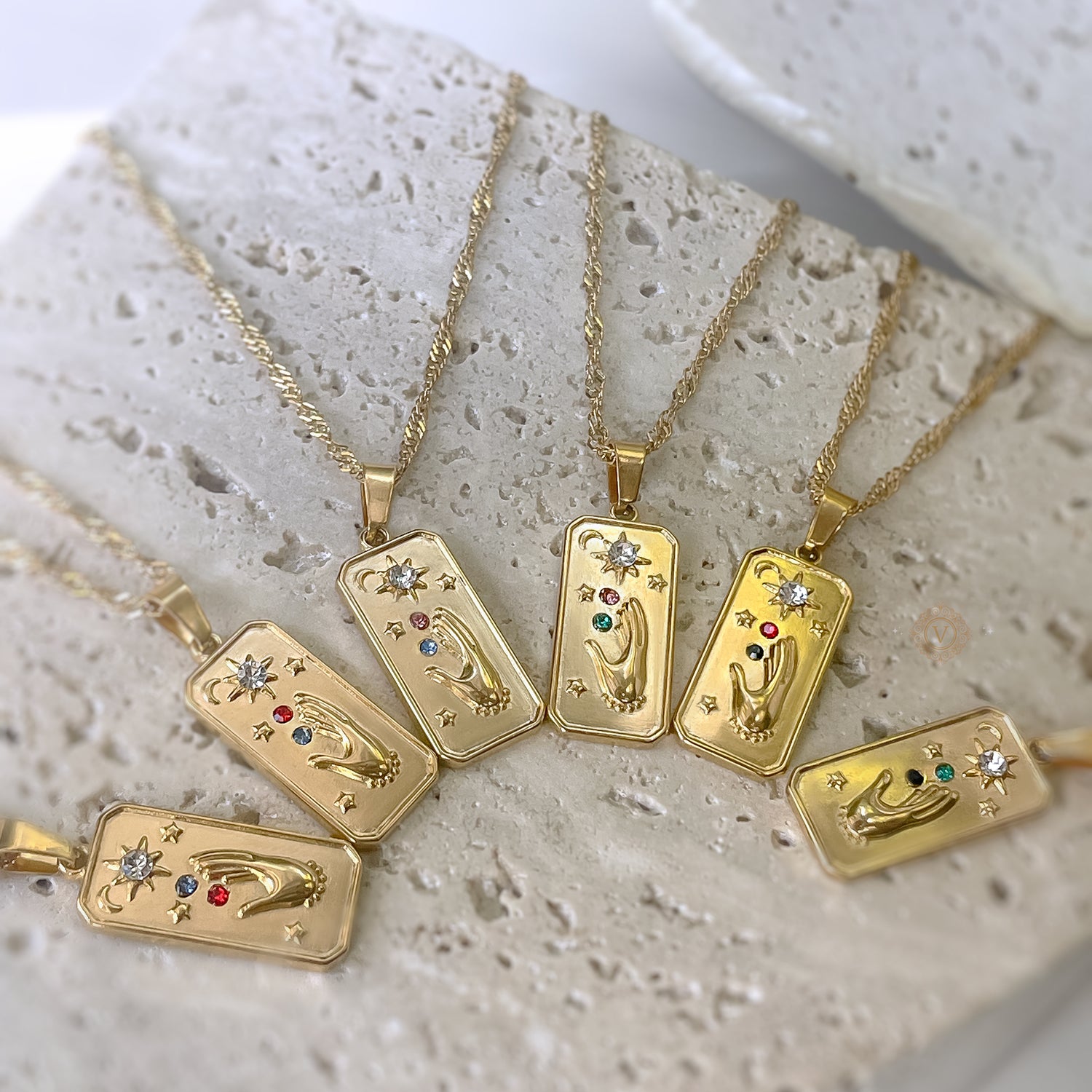 Gold necklaces with pendant designs on a textured surface
