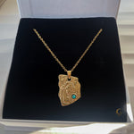 Gold necklace with a pendant on a black cushion inside a jewelry box