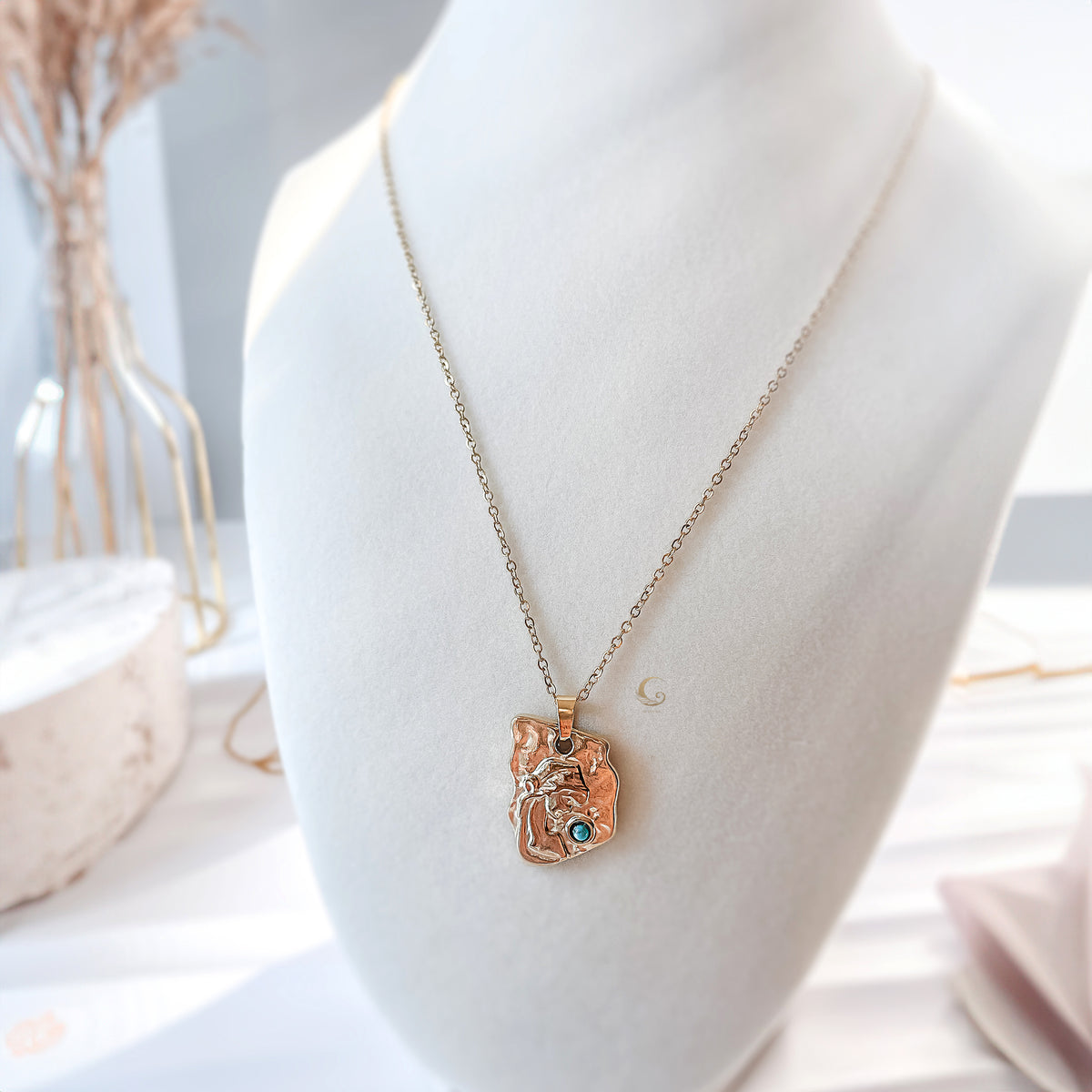 Necklace with a pendant on a mannequin bust against a neutral background