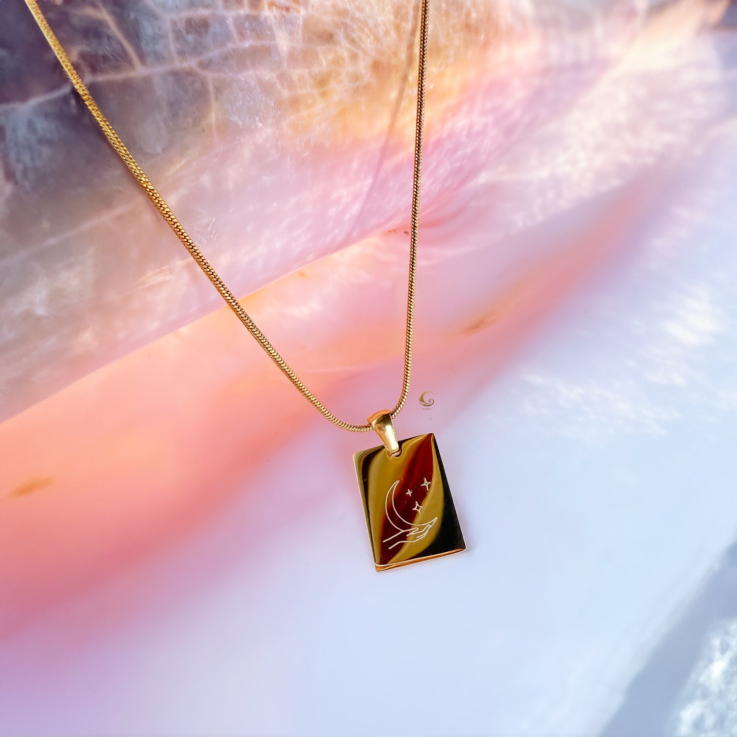 Gold necklace with a rectangular pendant on a soft, blurred background