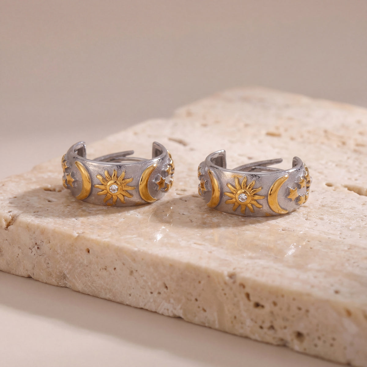 Pair of silver and gold toe rings on a stone surface