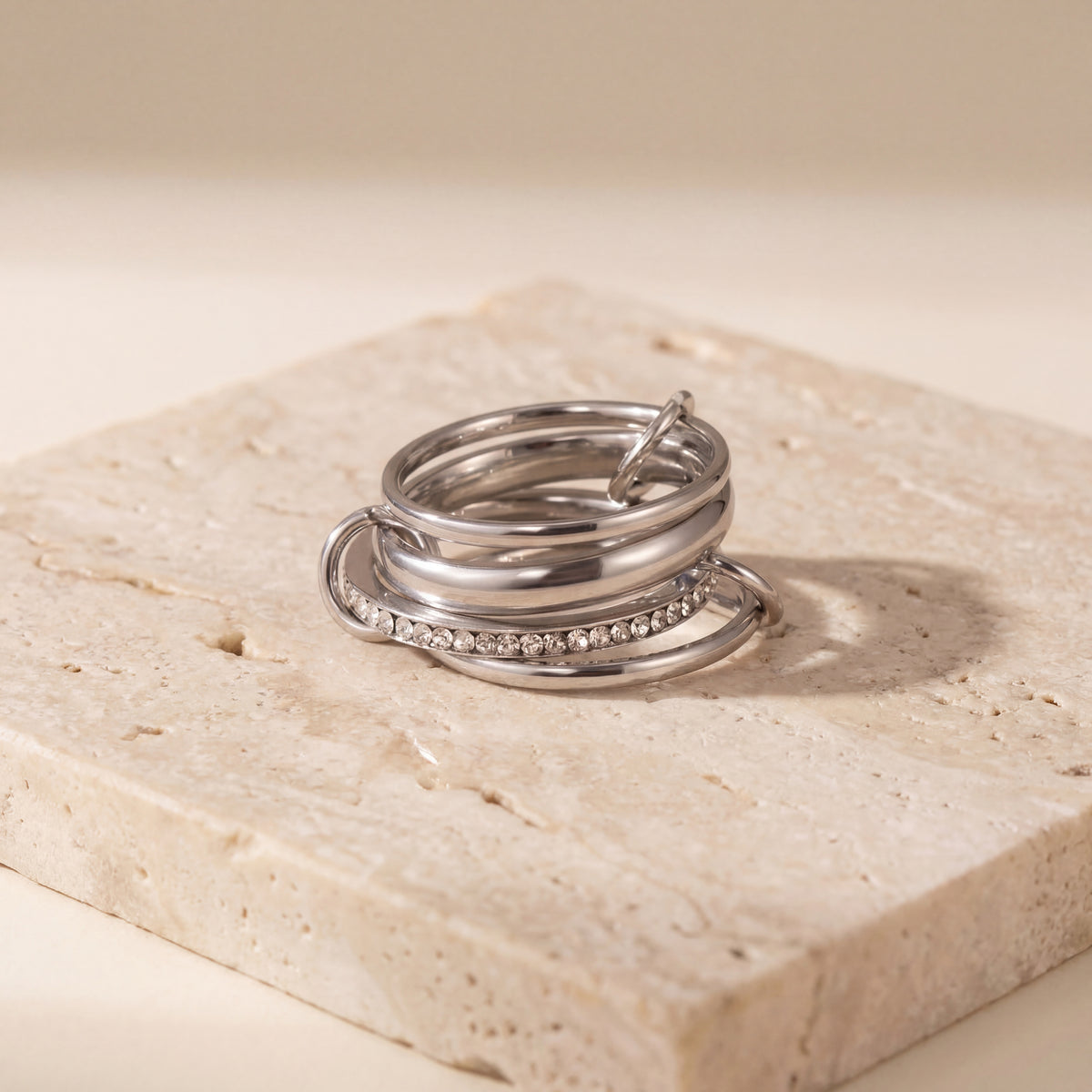 Silver ring with embedded stones on a beige stone surface
