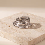 Silver ring with embedded stones on a beige stone surface