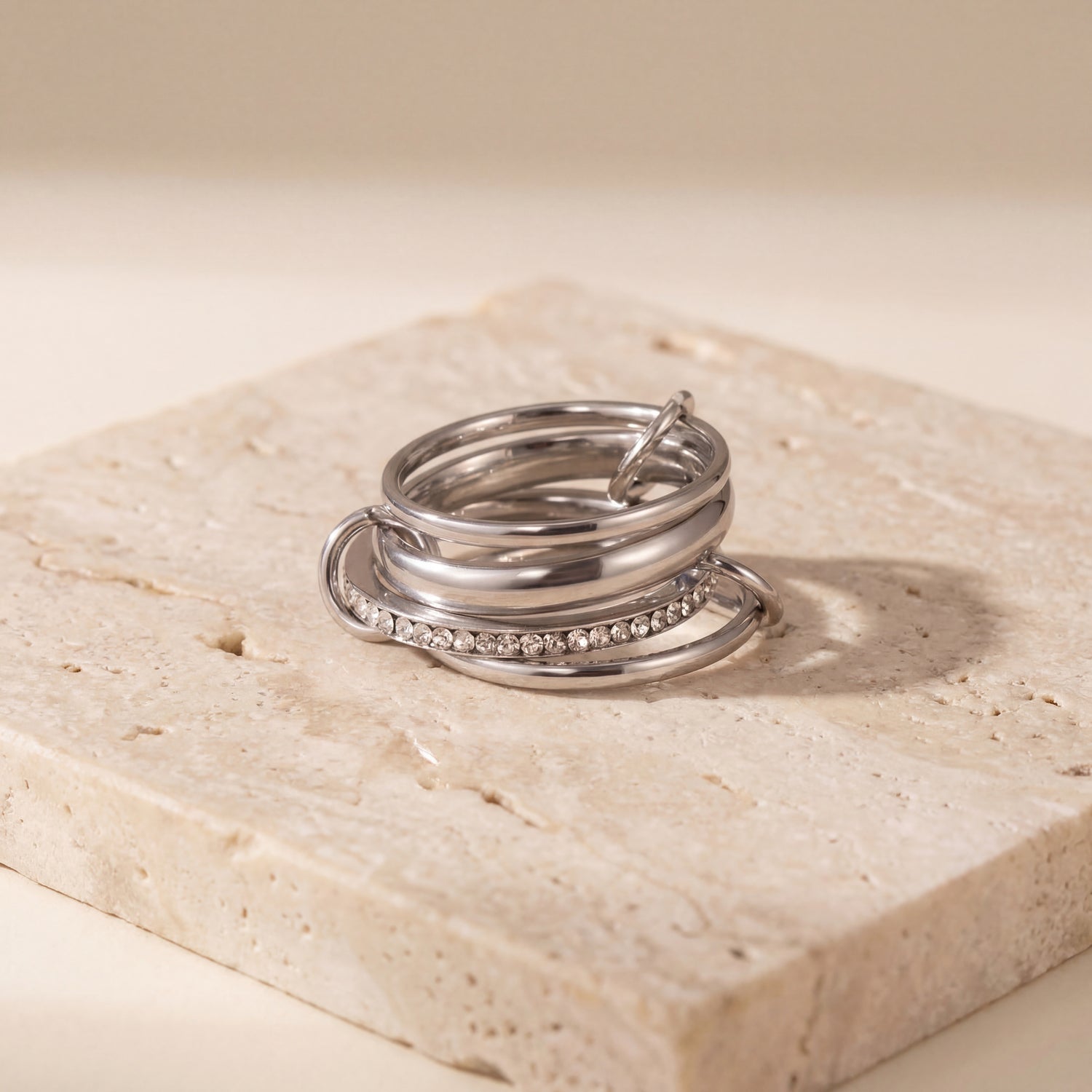 Silver ring with embedded stones on a beige stone surface