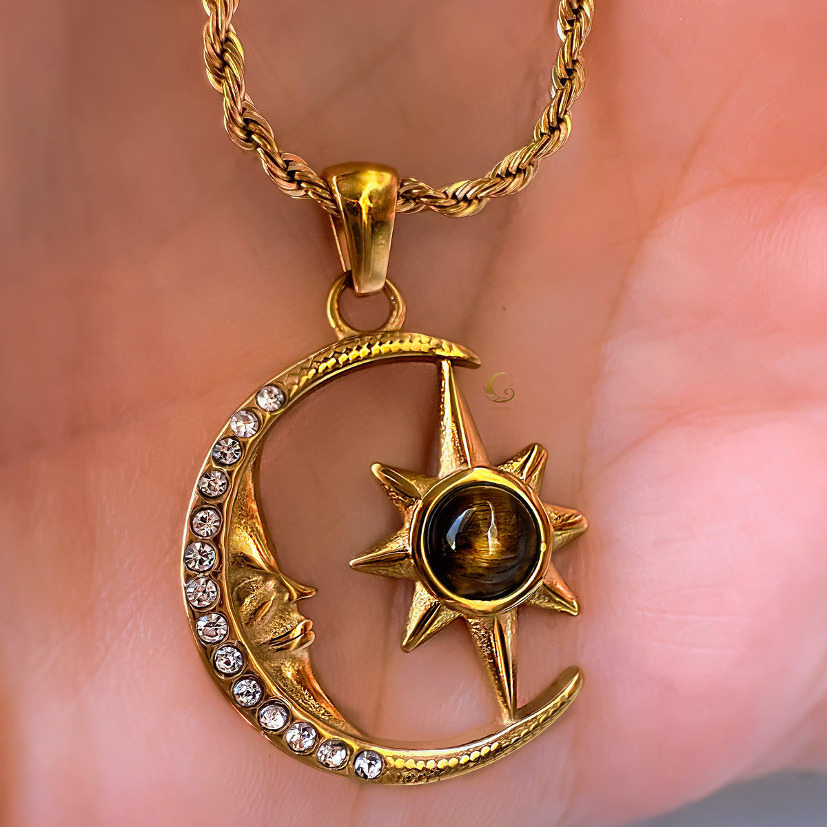 Gold necklace with a sun and moon pendant on a hand