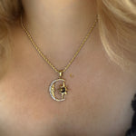 Gold necklace with a moon and star pendant on a person's neck.
