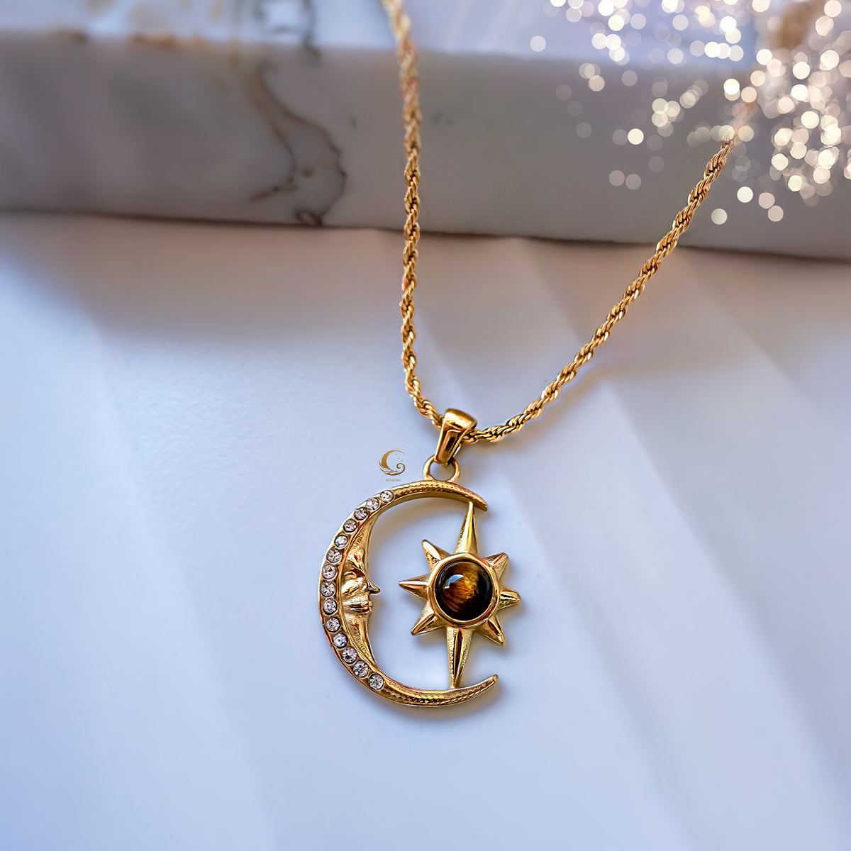 Gold necklace with a moon and star pendant on a marble surface