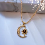 Gold necklace with a moon and star pendant on a marble surface