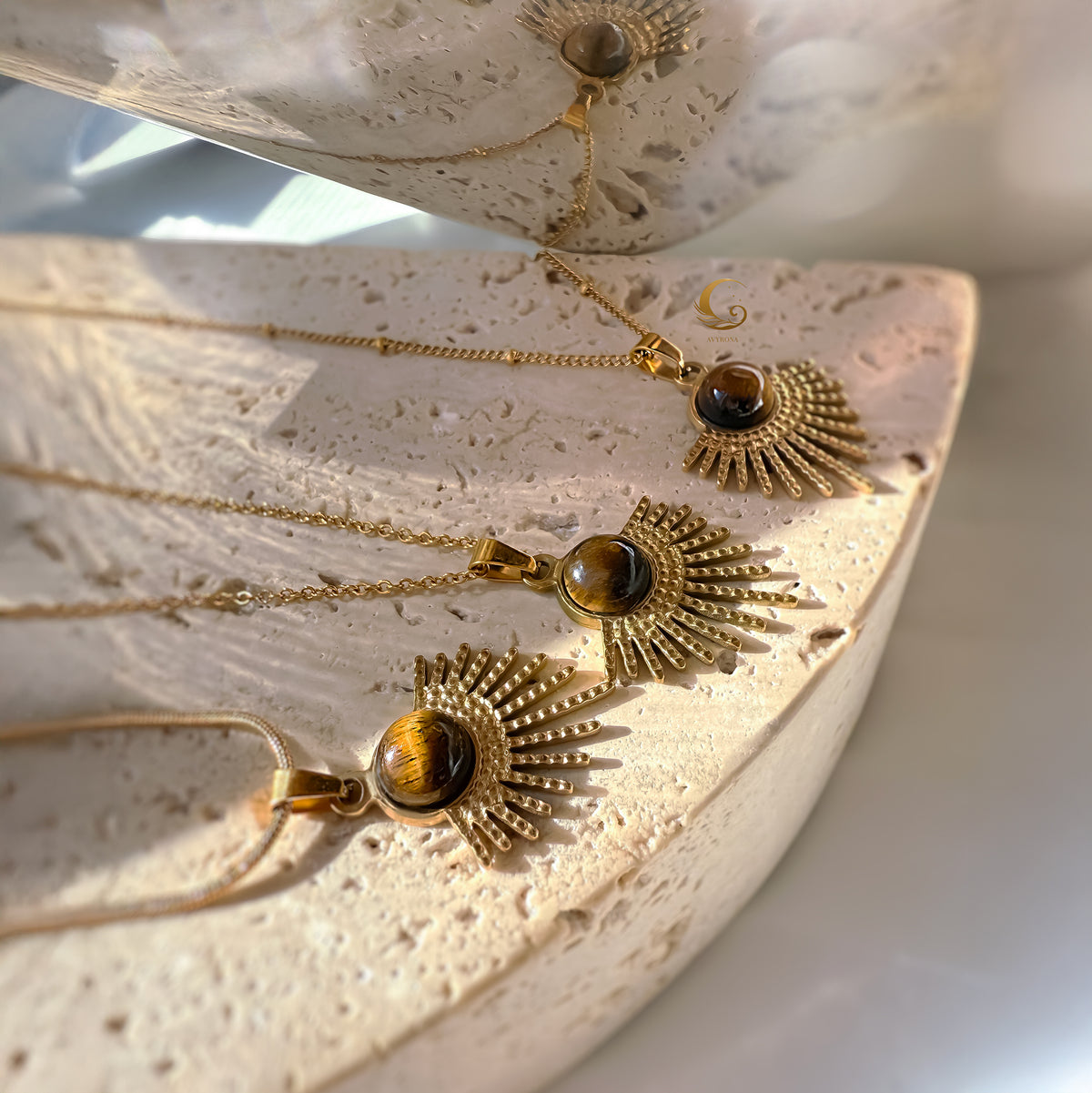Gold necklaces with pendant stones on a textured surface