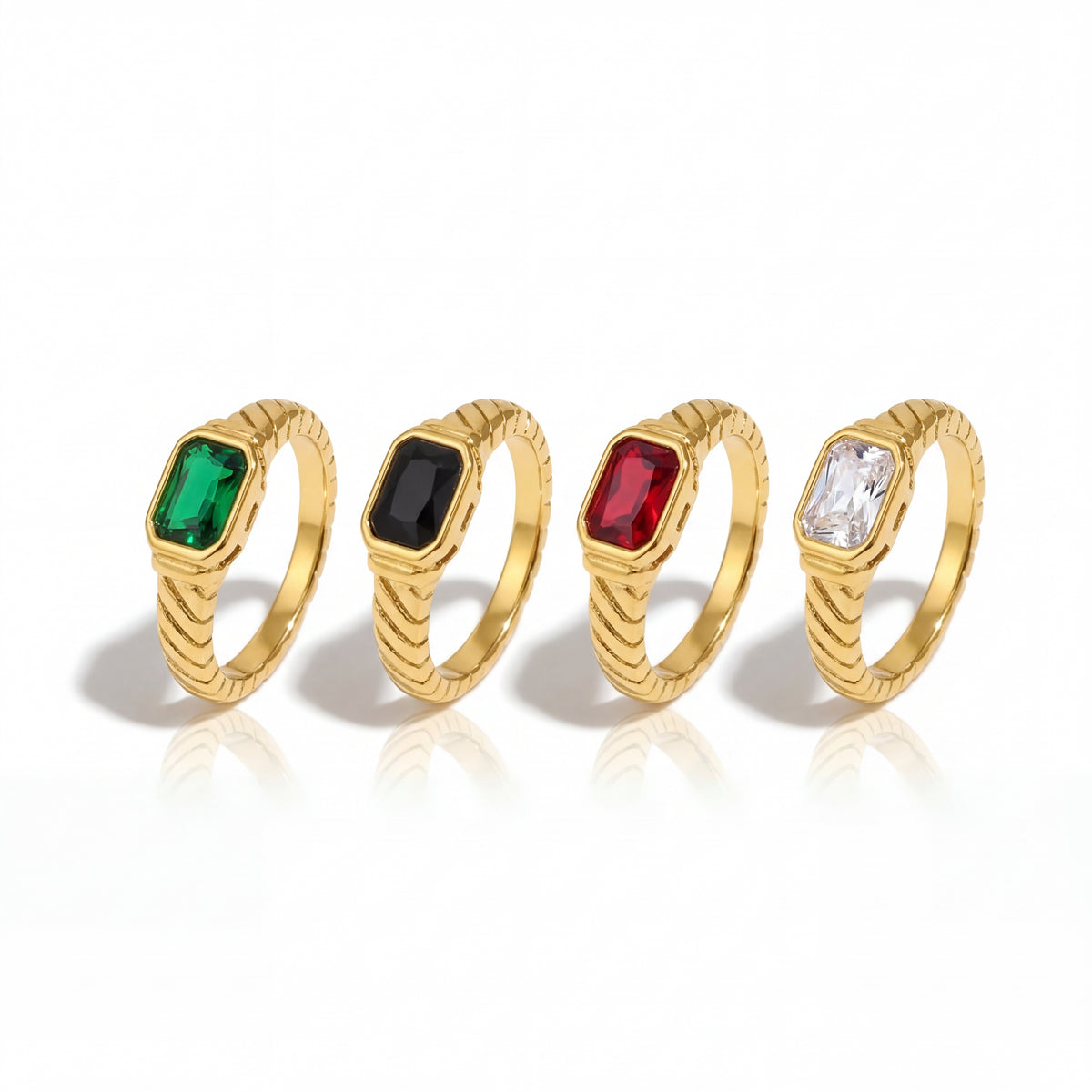Four gold rings with gemstones on a white background