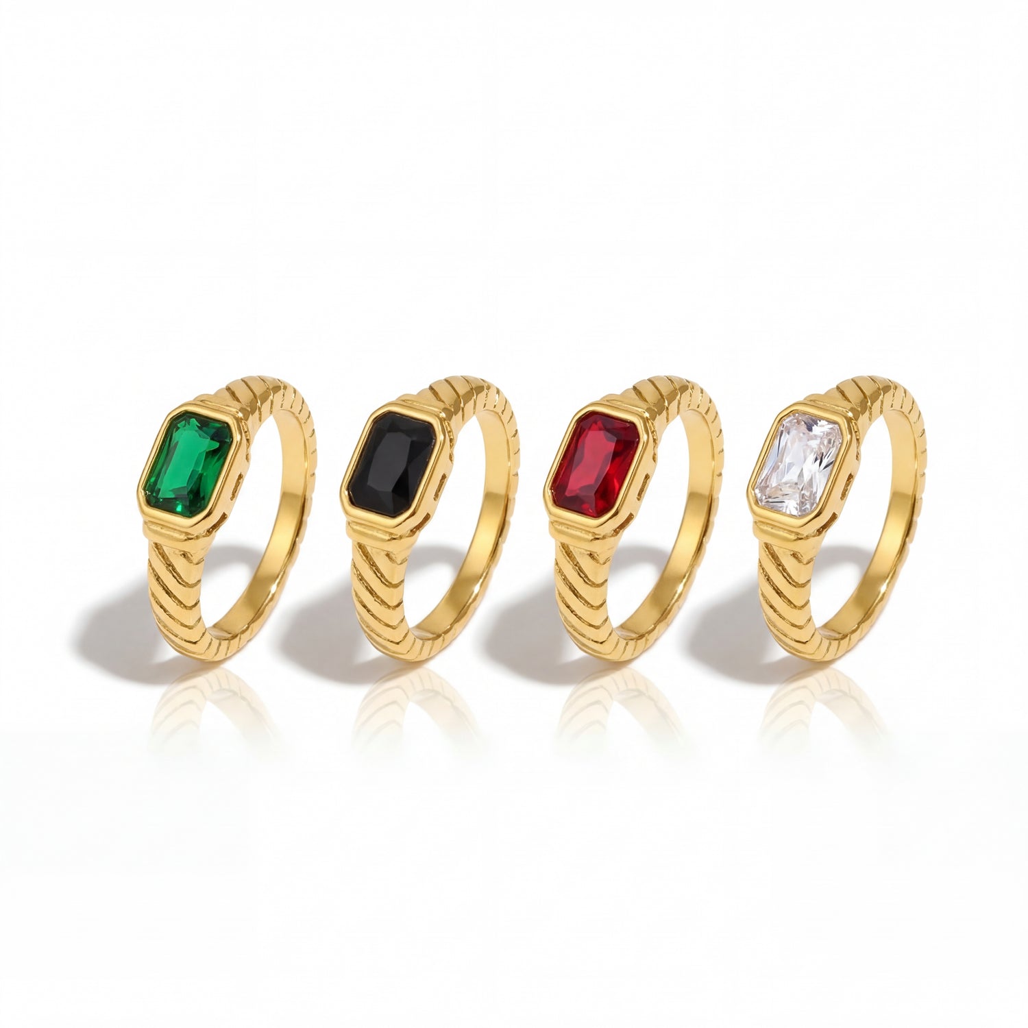 Four gold rings with gemstones on a white background