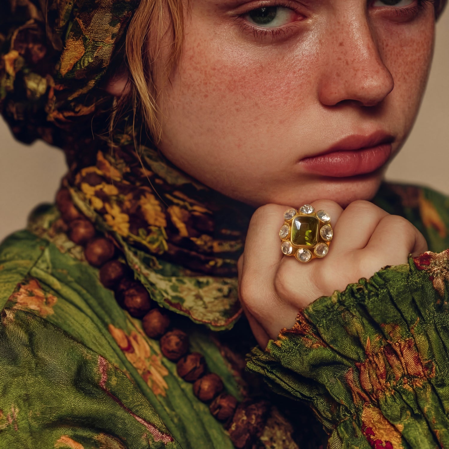 Person wearing a patterned headscarf and green outfit with a prominent ring.