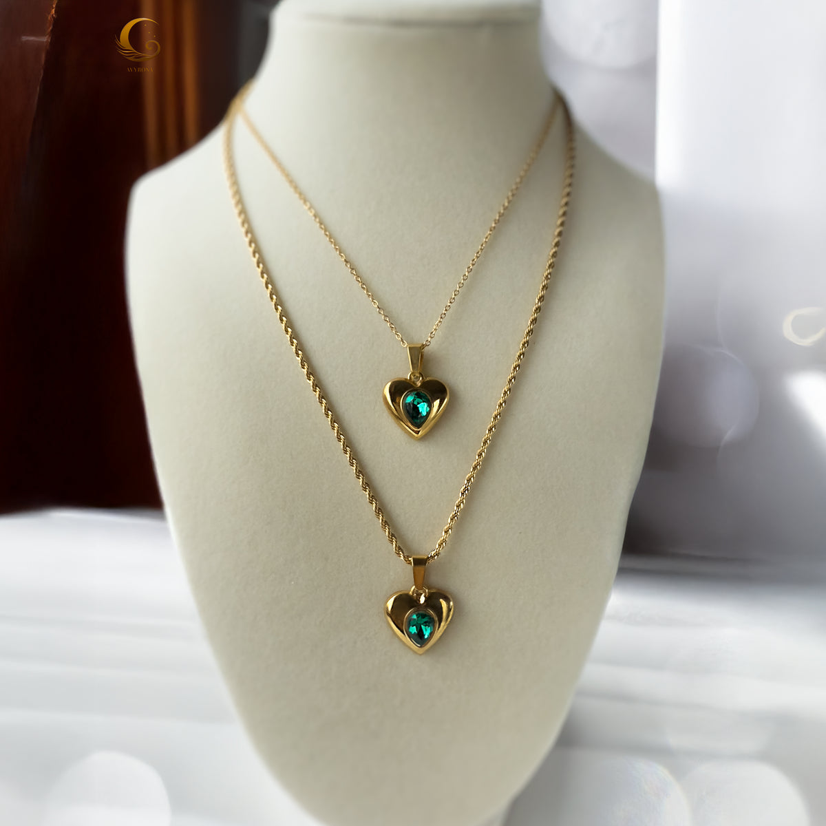 Layered necklace display on a mannequin with glowing emerald heart pendants