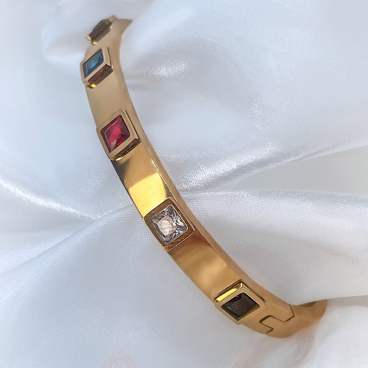 Gold bangle bracelet with colorful red, green, blue, and clear crystals, side clasp detail, Fire Collection – Avyrona