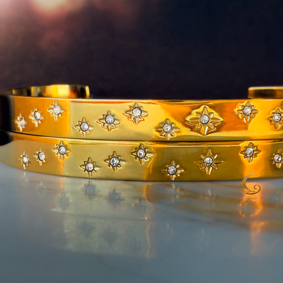Macro shot of star engravings with embedded zirconia on polished gold surface, showing the fine detail of the design.