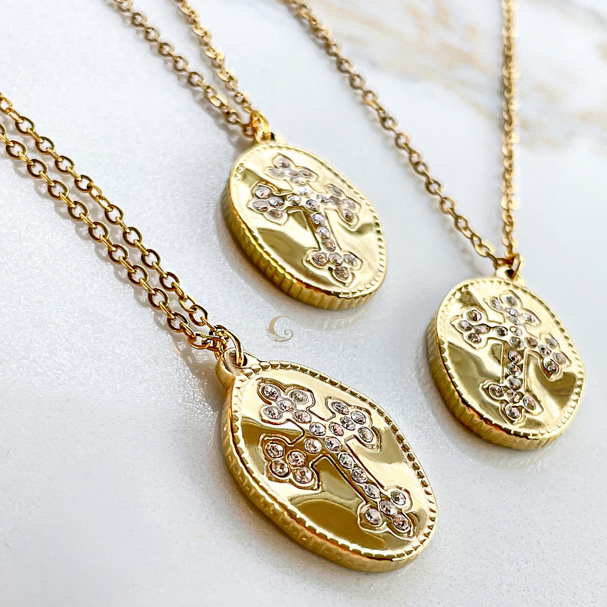 Close-up angled view showing the detailed craftsmanship of gold-plated cross necklaces with cubic zirconia on a marble background.