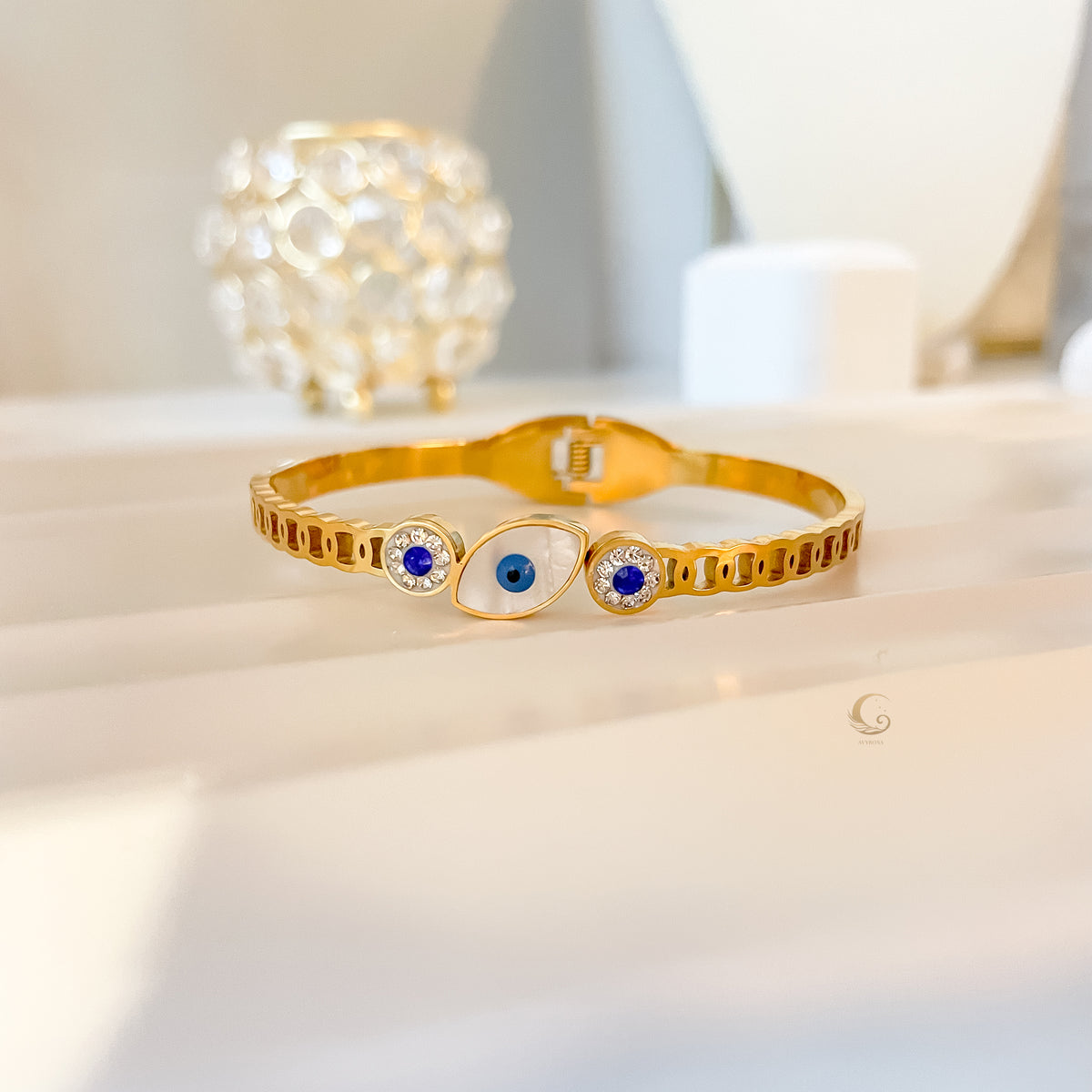 Full view of Elina Evil Eye bangle bracelet with crystals, against soft background